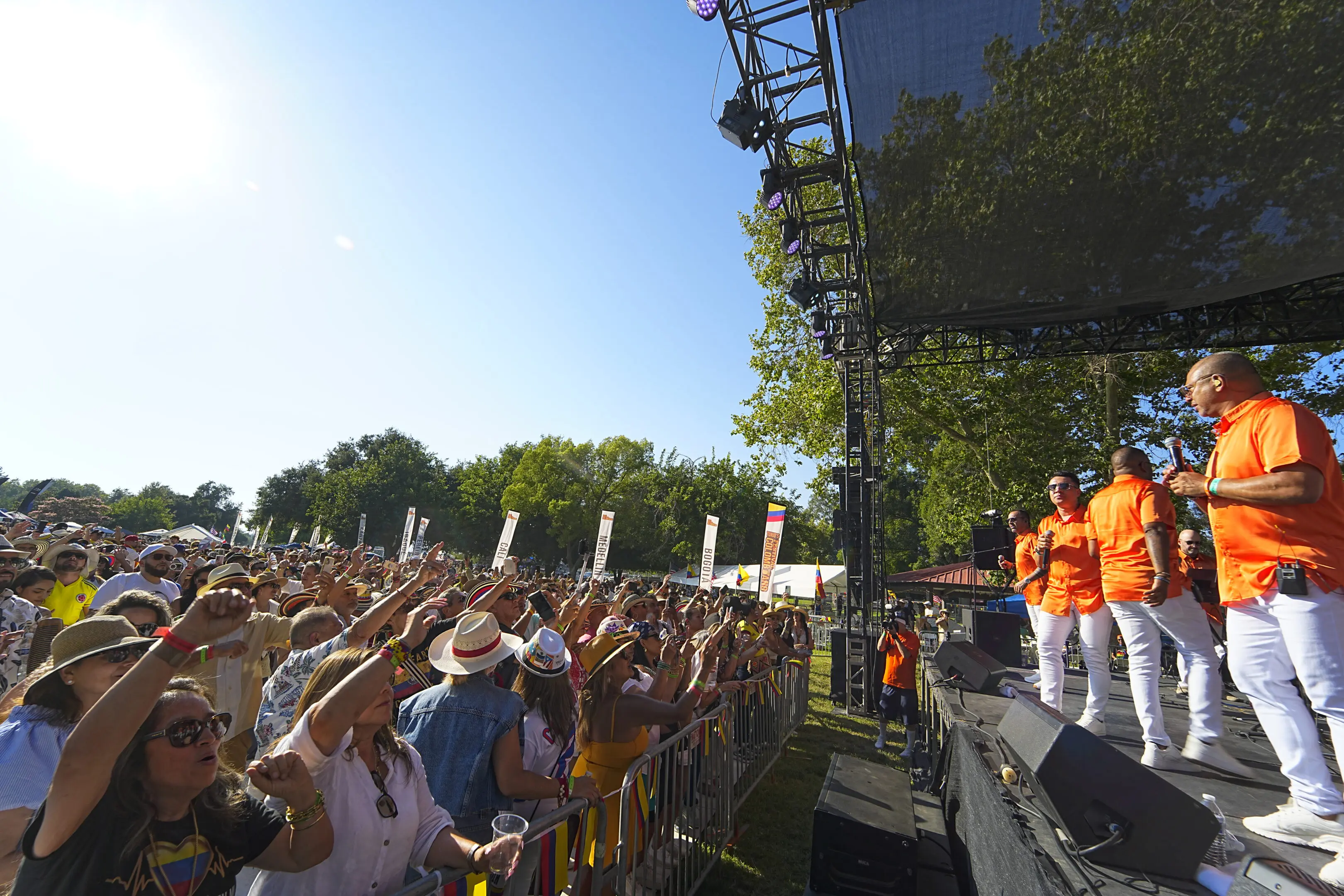 Crowd enjoying a live outdoor concert with performers on stage.